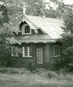 Vue en angle de la chapelle, qui montre la bordure de rive de forme simple des pignons et le support de croix simple, en bois, au faîte du pignon, 1984.; Parks Canada | Parcs Canada, Robert Hunter, 1984.