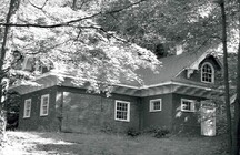Side elevation of the Stable and Carriage House, showing the regular fenestration, the large sliding doors and the round headed apertures at the gable ends, 1984.; Parks Canada | Parcs Canada, Robert Hunter, 1984.