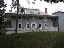Vue de la façade générale du manoir Papineau, qui montre sa volumétrie fortement articulée composée d’un volume central imposant, au toit en croupe tronqué à larges débords, 2001.; Parks Canada | Parcs Canada, Yvan Fortier, 2001.