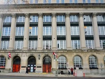Vue de la façade principale de l'Édifice Wellington mettant de l'emphase sur l’emploi de matériaux de finition de qualité à l’extérieur, y compris le revêtement lisse en pierre calcaire avec une base en granit et des panneaux d’allège, 2011.; Parks Canada | Parcs Canada, M. Therrien, 2011.
