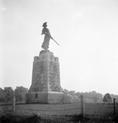 Vue historique de Madeleine de Verchères, qui montre la statue de bronze fixée au sommet d'une tour conique, 1934.; Library and Archives Canada | Bibliothèque et Archives Canada, PA-056837, C. M. Johnson, 1934.